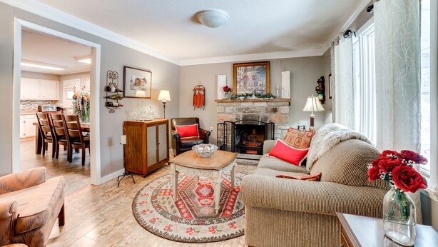 A living room with a fireplace, a dining area, and a kitchen visible through an open doorway. - Rector Home w/ Hot Tub ~ 6 Mi to Ligonier! (Ligonier)