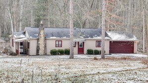 A single-story house with a red garage door, a chimney, and a small porch. - Rector Home w/ Hot Tub ~ 6 Mi to Ligonier! (Ligonier)