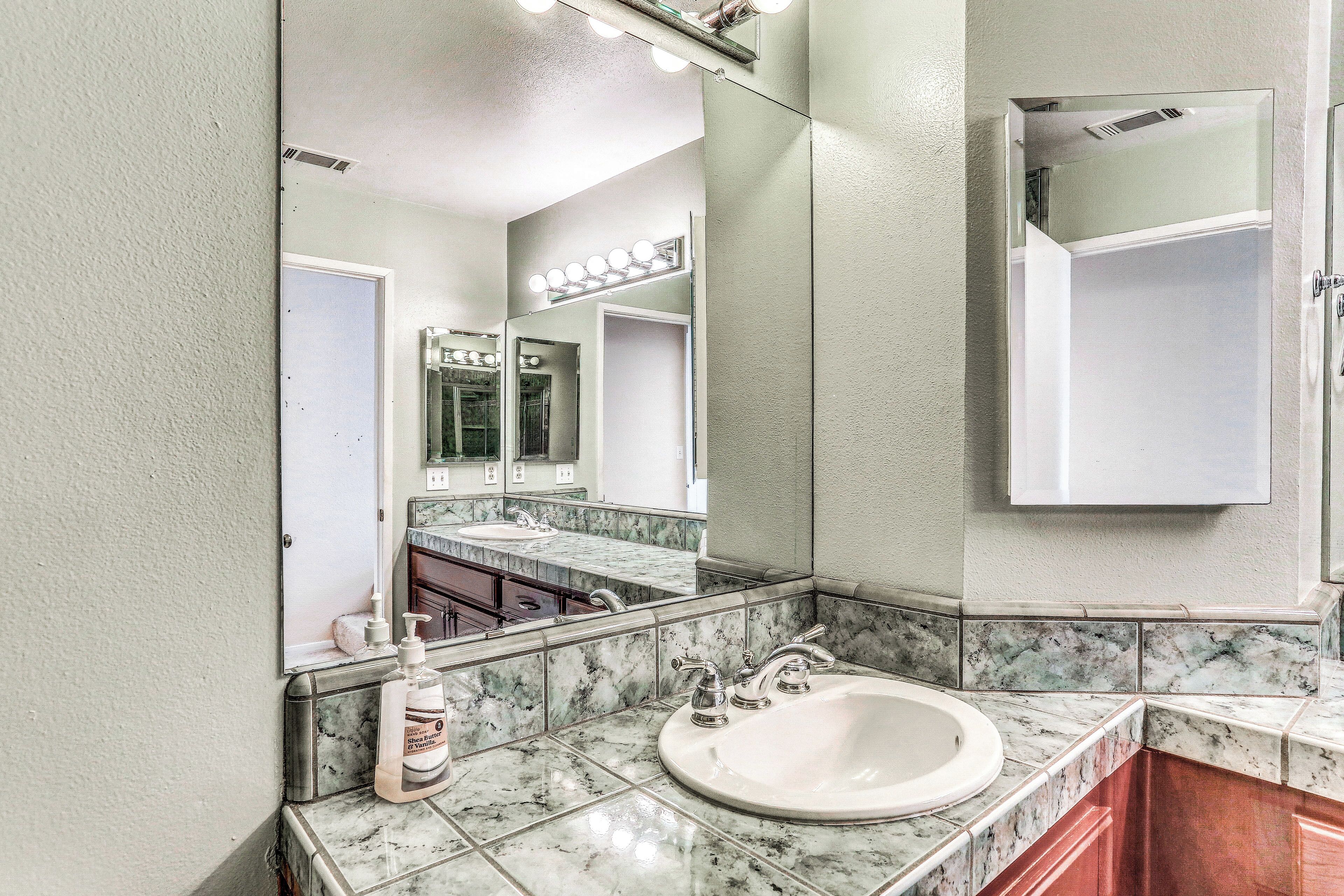 A bathroom with a marble sink, a large mirror, and a vanity cabinet.