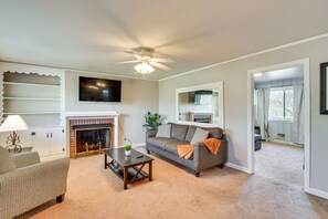 A living room with a fireplace, a sofa, a coffee table, and a television. - Greenville Home w/ Private Yard Near Downtown! (Greenville)