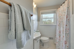 A bathroom with a toilet, sink, and window. - Greenville Home w/ Private Yard Near Downtown! (Greenville)