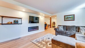 A modern living room with a flat-screen TV, a fireplace, a sofa, and a rug. - Waynesville Studio Suite < 1 Mi to Downtown! (Waynesville)