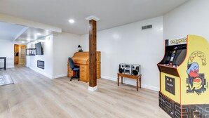 A spacious room with a wooden desk, a computer, and a Pac-Man arcade machine. - Waynesville Studio Suite < 1 Mi to Downtown! (Waynesville)