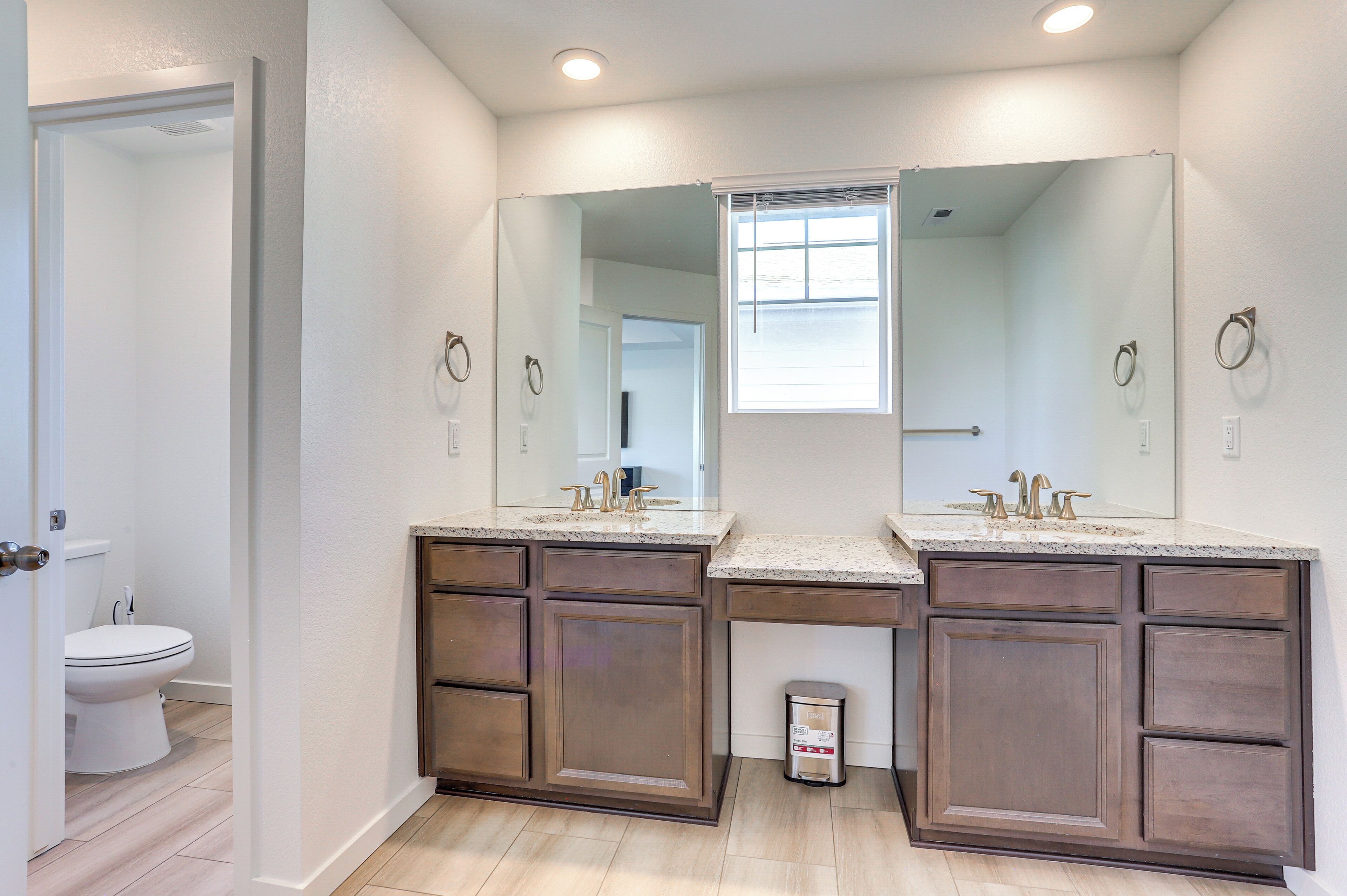 A bathroom with two sinks, a toilet, and a window.