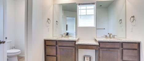 A bathroom with two sinks, a toilet, and a window.