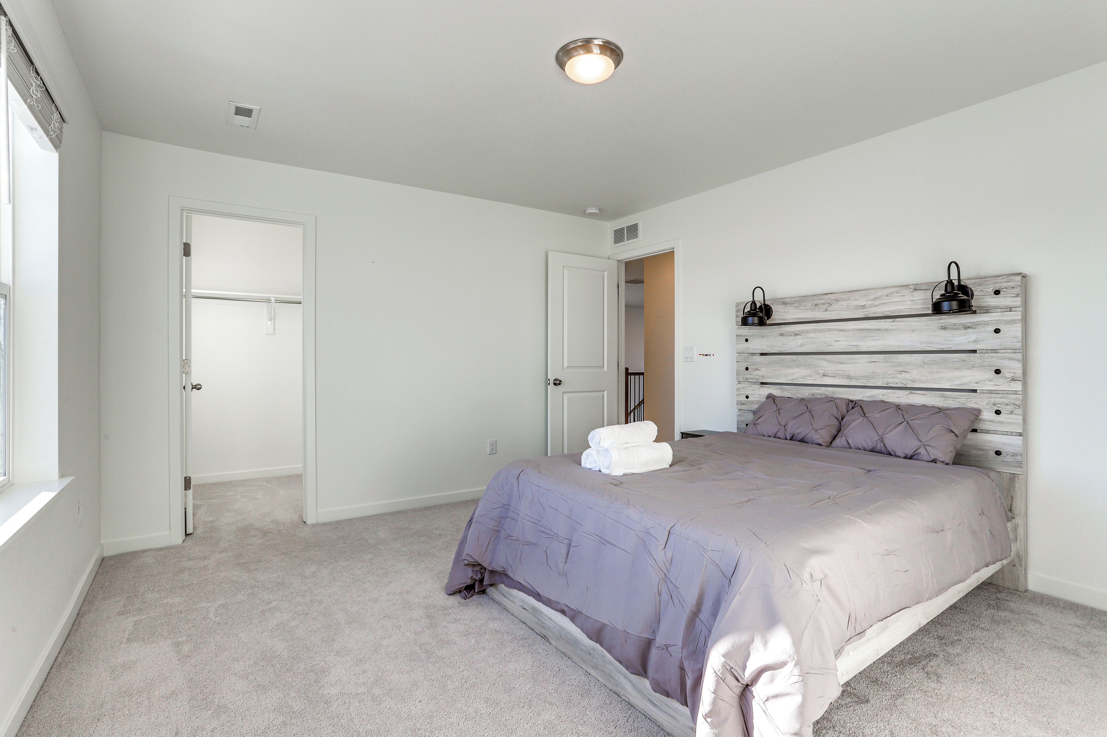 A bedroom with a bed, a headboard, and a window.