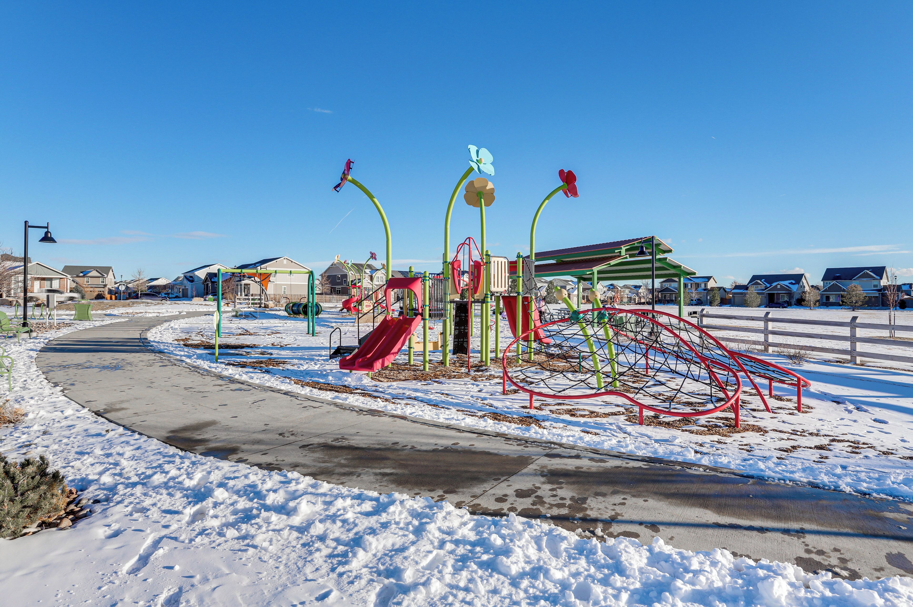 A playground with slides and climbing structures, surrounded by snow.