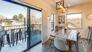 Un comedor con mesa y sillas de madera, ventanas amplias y vistas al exterior.