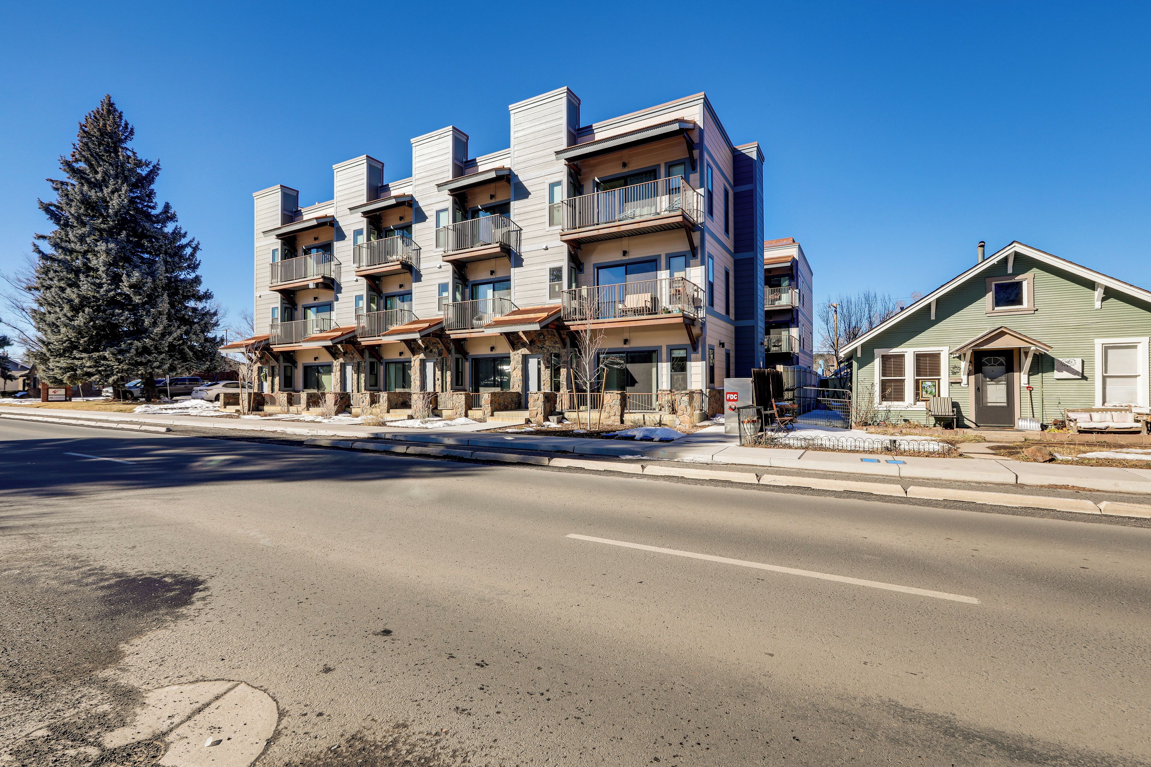 A multi-story residential building with balconies, a driveway, and a snow-covered ground.