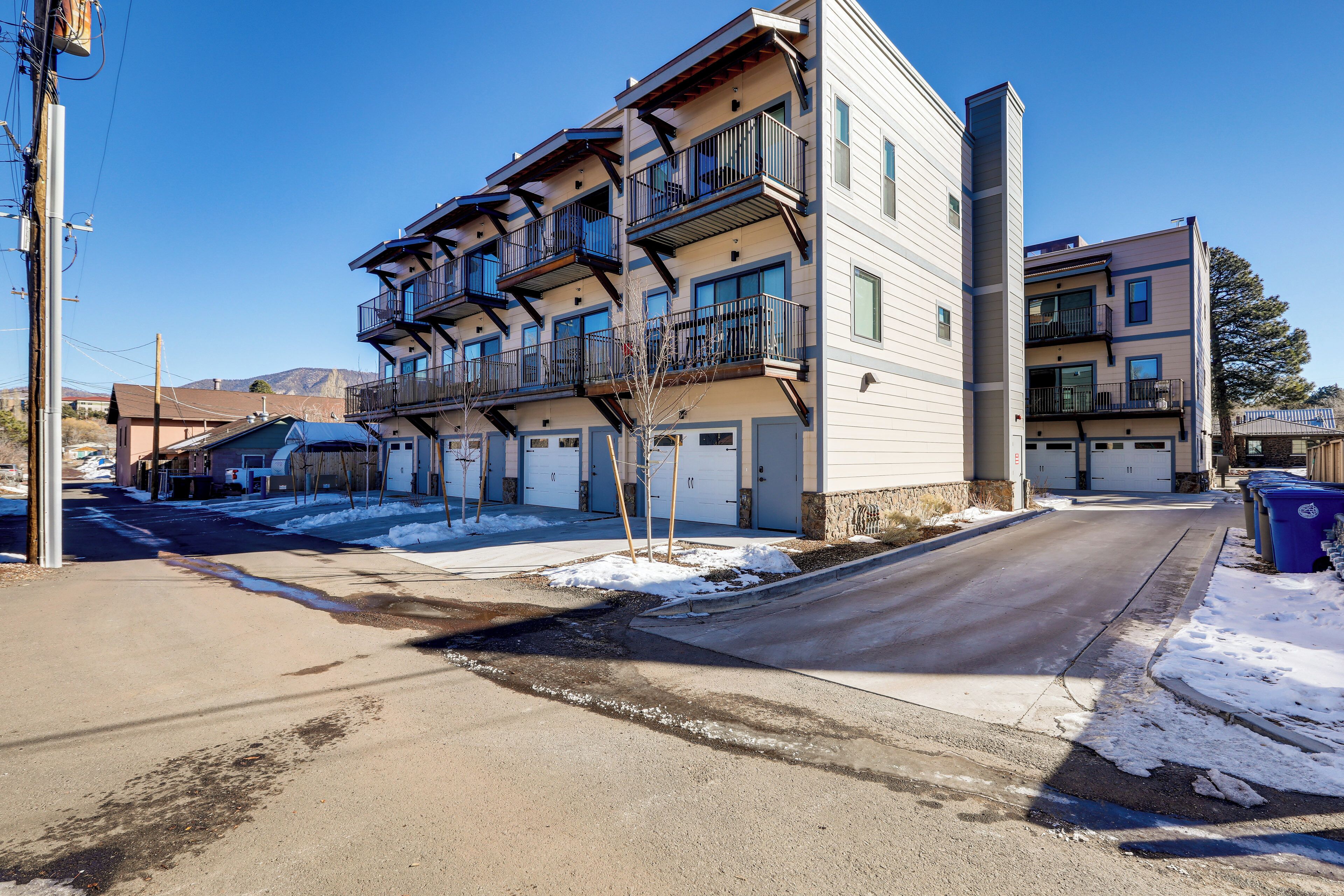 A multi-story residential building with balconies, a garage, and a clear sky.