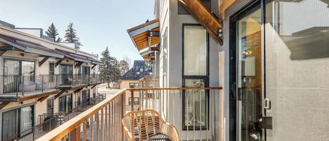 A balcony with a wicker chair and a glass door leading to a room.