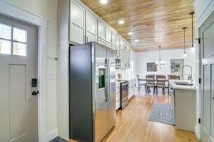 Una cocina moderna con armarios blancos, electrodomésticos de acero inoxidable y techo de madera.