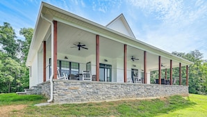 A house with a covered porch, stone foundation, and large windows. - Dale Hollow Cottage w/ Covered Porch & Lake Views! (Burkesville)