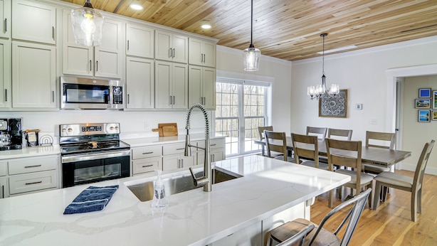 A modern kitchen with white cabinets, stainless steel appliances, and a large island with seating. - Dale Hollow Cottage w/ Covered Porch & Lake Views! (Burkesville)