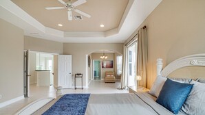 A bedroom with a large bed, a ceiling fan, and a view of the hallway. - Hot Tub + Fire Pit: Spacious Cape Coral Oasis! (Cape Coral)