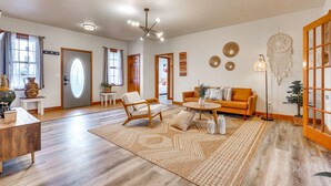 Un salon spacieux doté d’un plancher en bois, d’un ensemble de canapés, d’une table basse et d’un attrape-rêves décoratif.