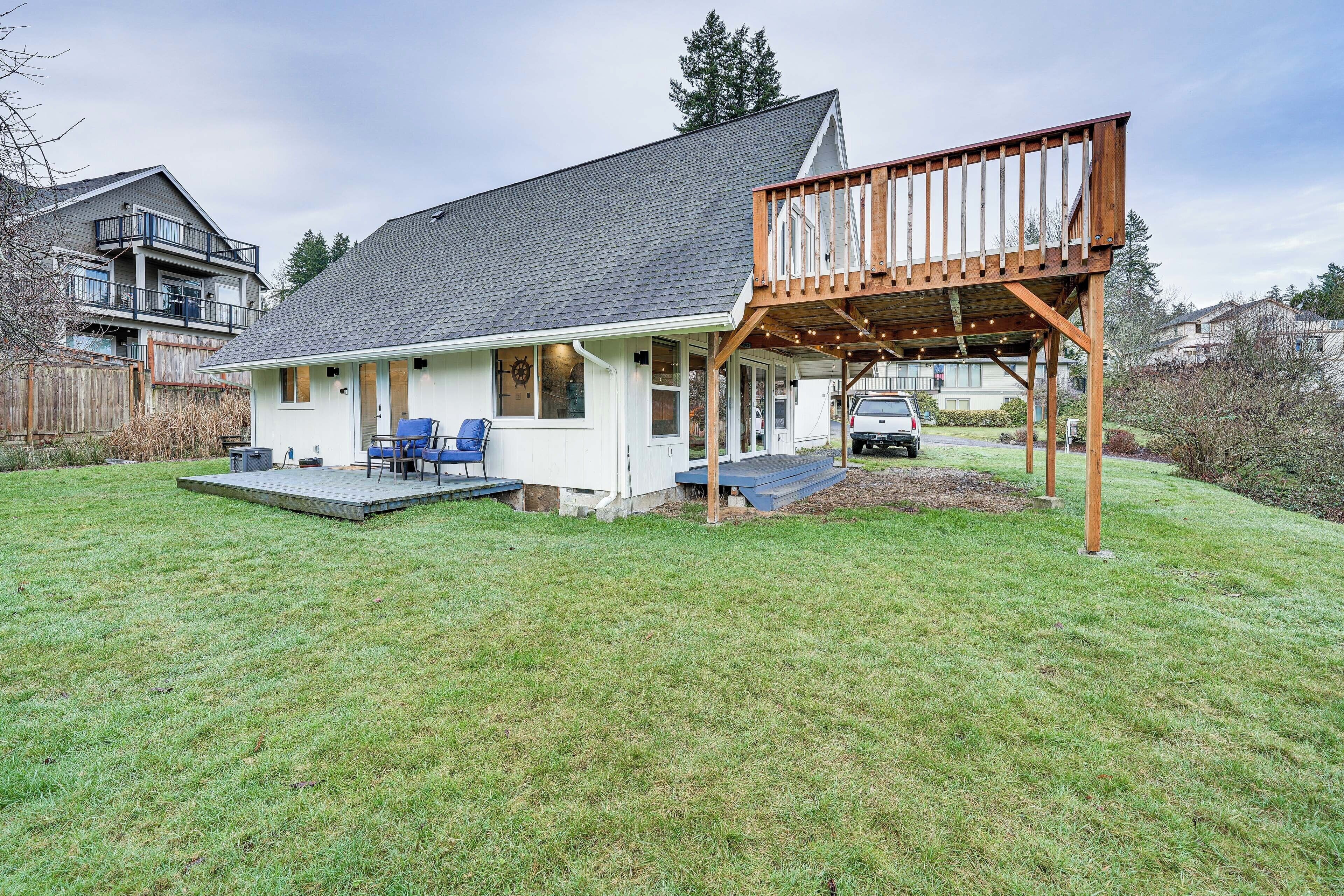 A house with a covered patio, a deck, and a lawn.