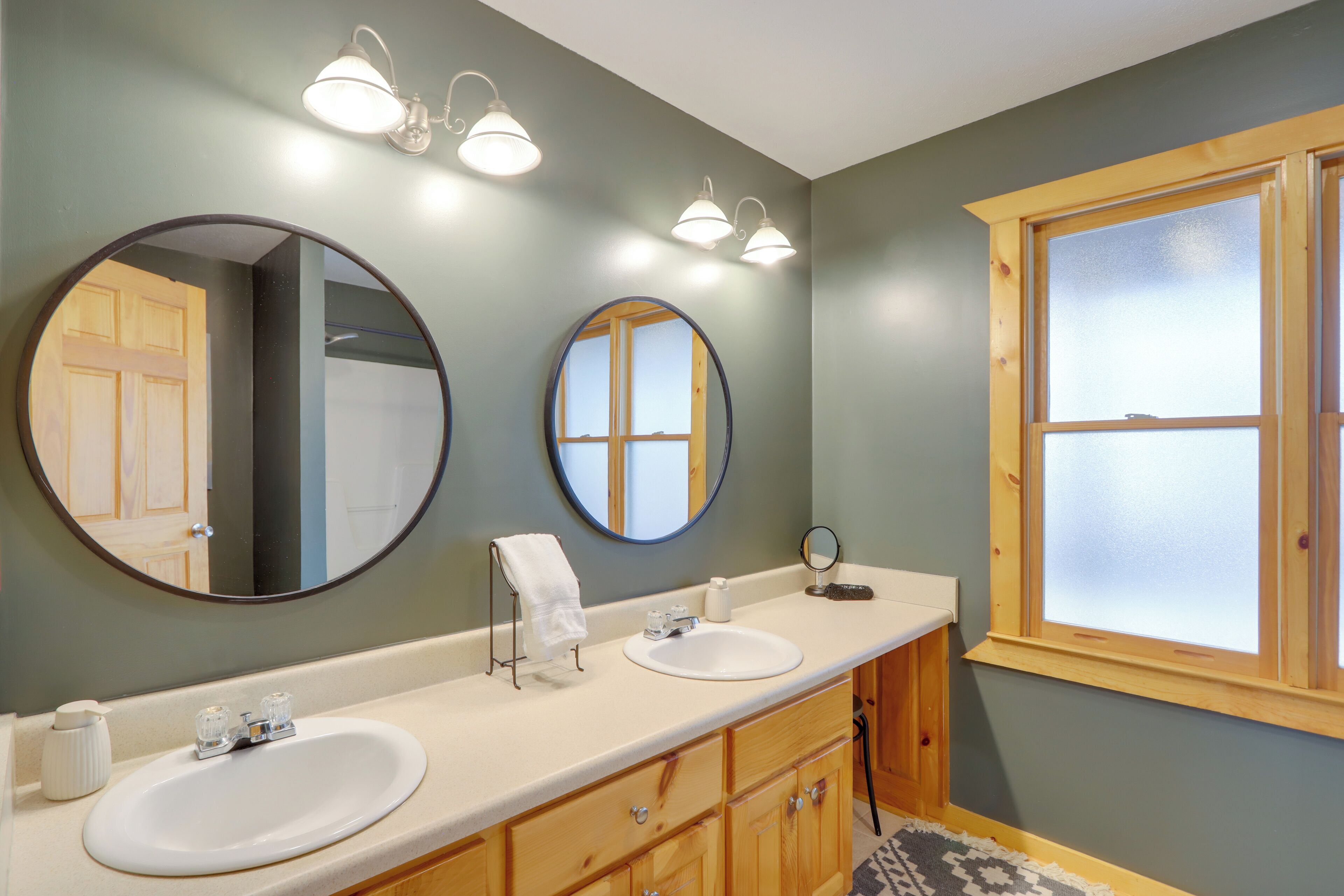 Une salle de bain avec deux lavabos, un miroir et une fenêtre.