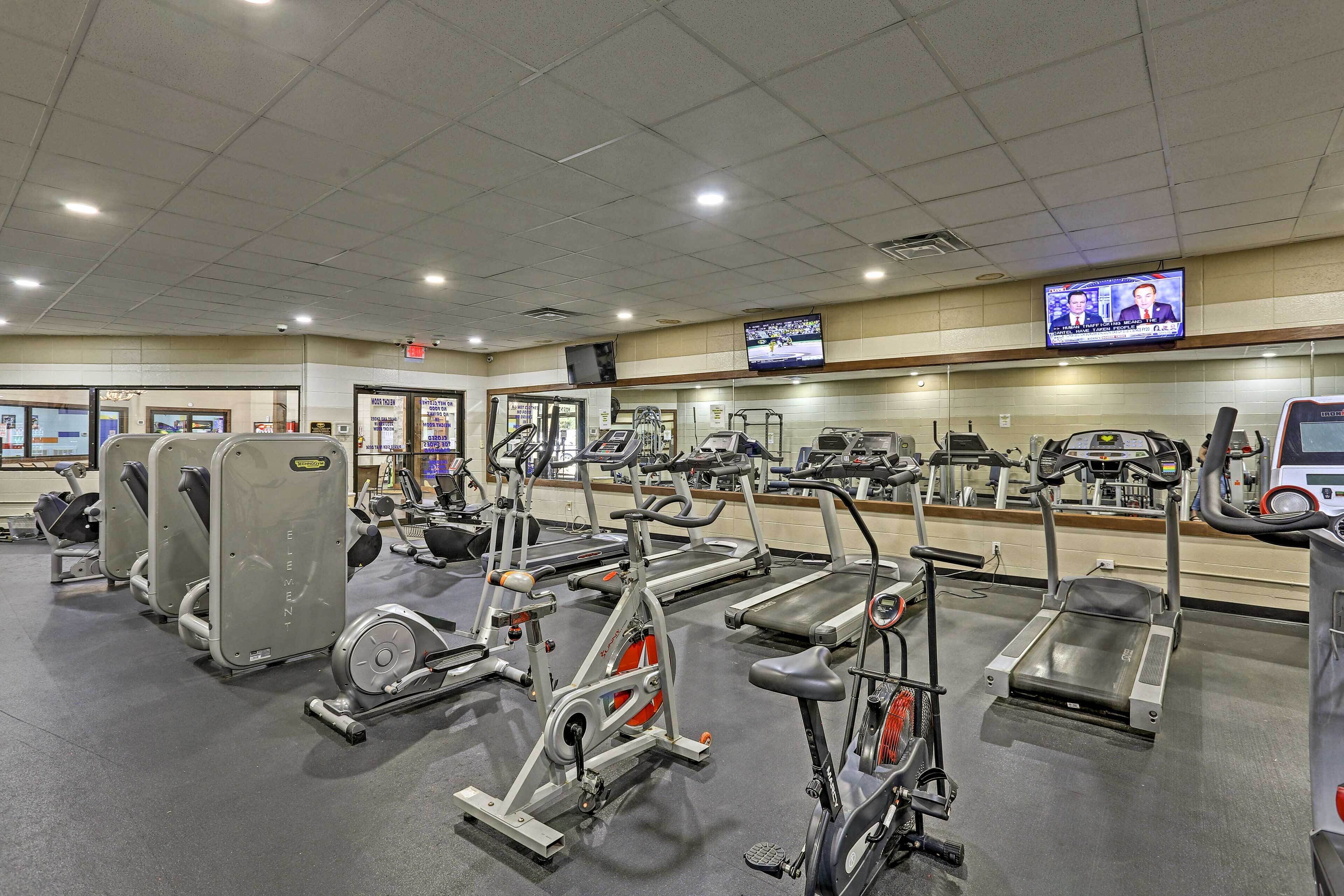 Une salle de sport équipée de divers appareils d’exercice, notamment des tapis de course et des appareils de musculation elliptique.