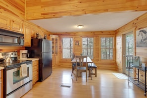 A wooden cabin interior with a kitchen, dining table, chairs, and a refrigerator. - Peaceful Ellijay Cabin: Pool Access & Resort Perks (Ellijay)