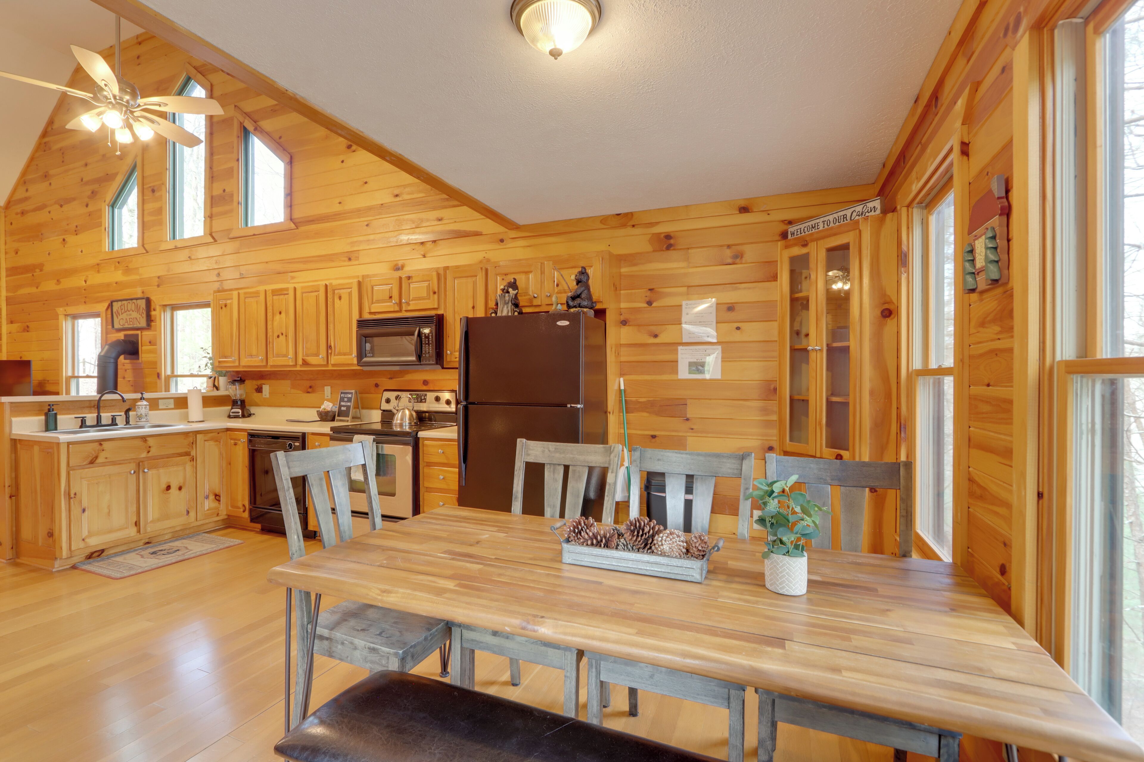 A wooden cabin interior with a kitchen, dining table, and chairs.