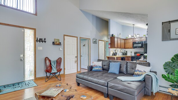 A spacious living room with a leather sofa, wooden coffee table, and a dining area with a kitchen in the background. - Fire Pit, Pool & Beach Access: Tobyhanna Home! (Tobyhanna)