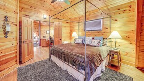 A wooden cabin bedroom with a four-poster bed, a ceiling fan, and a window with blinds. - Waterfront Watauga Lake Home w/ Private Dock! (Butler)