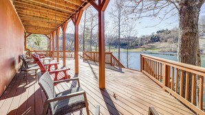 A covered deck with wooden railings and chairs overlooking a lake. - Waterfront Watauga Lake Home w/ Private Dock! (Butler)
