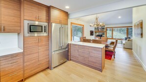 Una cocina moderna con armarios de madera, electrodomésticos de acero inoxidable y una isla central.