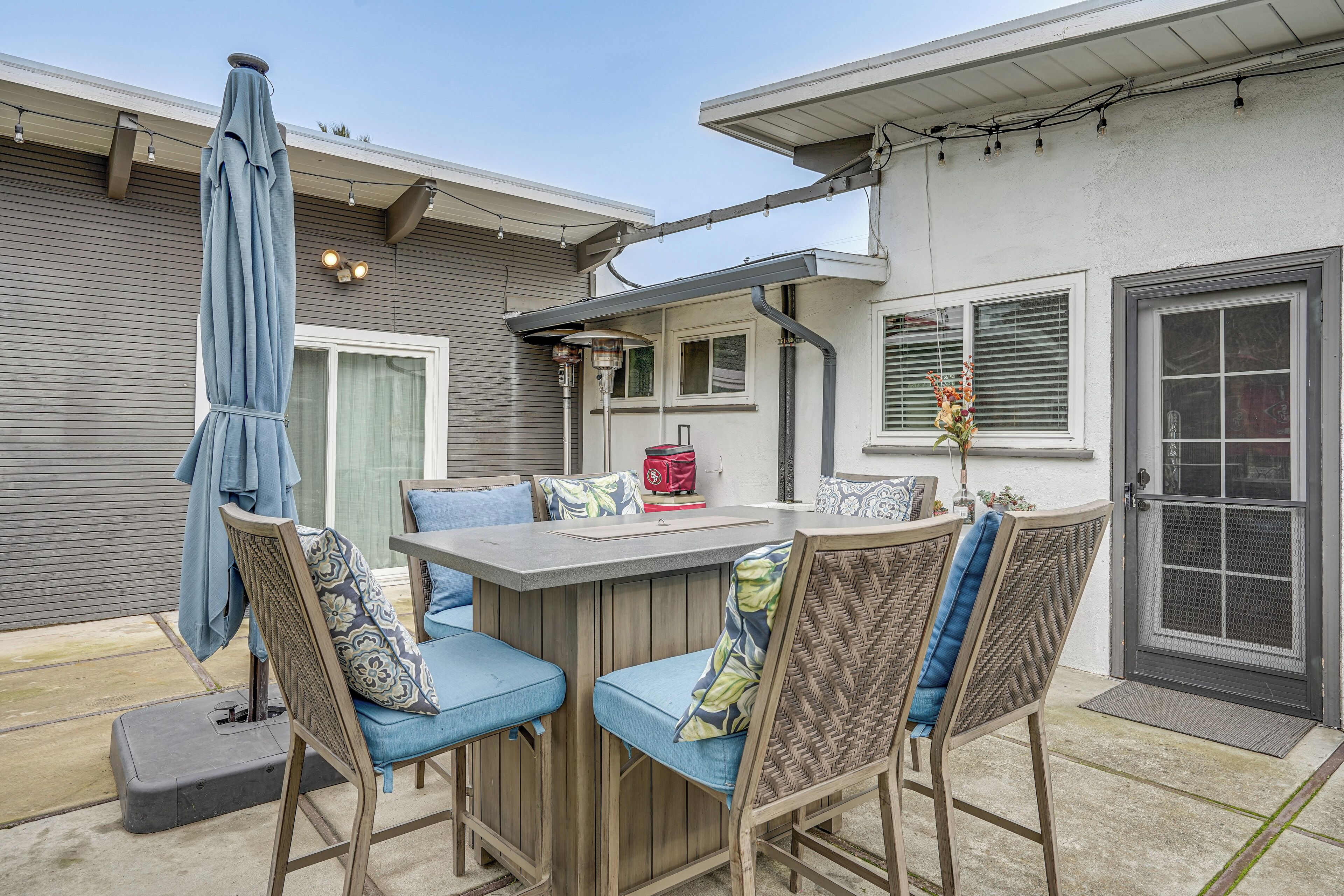 An outdoor patio with a bar area, cushioned chairs, and a covered umbrella.