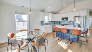 Een moderne keuken met witte kasten, een centraal eiland met barkrukken en hanglampen.