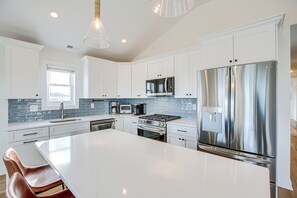 A modern kitchen with white cabinetry, stainless steel appliances, and a large island.