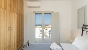Ein Schlafzimmer mit einem Bett, einem Holzschrank und einem Balkon mit Tisch und Stühlen.