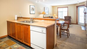 A kitchen with a dishwasher, a sink, and a dining area with a table and chairs.