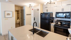 A modern kitchen with a large island, black appliances, and white cabinetry. - 2204 - Two Bedroom Deluxe Eagle Springs East 2 Condo by RedAwning (Solitude)