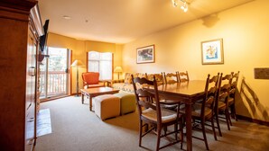 A dining area with a wooden table and chairs, a sofa, and a window with blinds. - 3309A - One Bedroom Standard Powderhorn Lodge 1 Condo by RedAwning (Salt Lake City)
