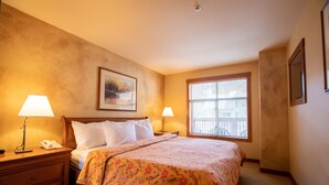A hotel room with a bed, two bedside lamps, a nightstand, a framed picture on the wall, and a window with blinds. - 3309A - One Bedroom Standard Powderhorn Lodge 1 Condo by RedAwning (Salt Lake City)