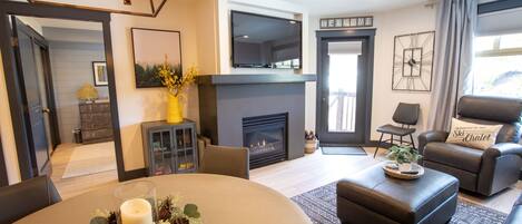 A modern living room with a fireplace, comfortable seating, and a television mounted on the wall.
