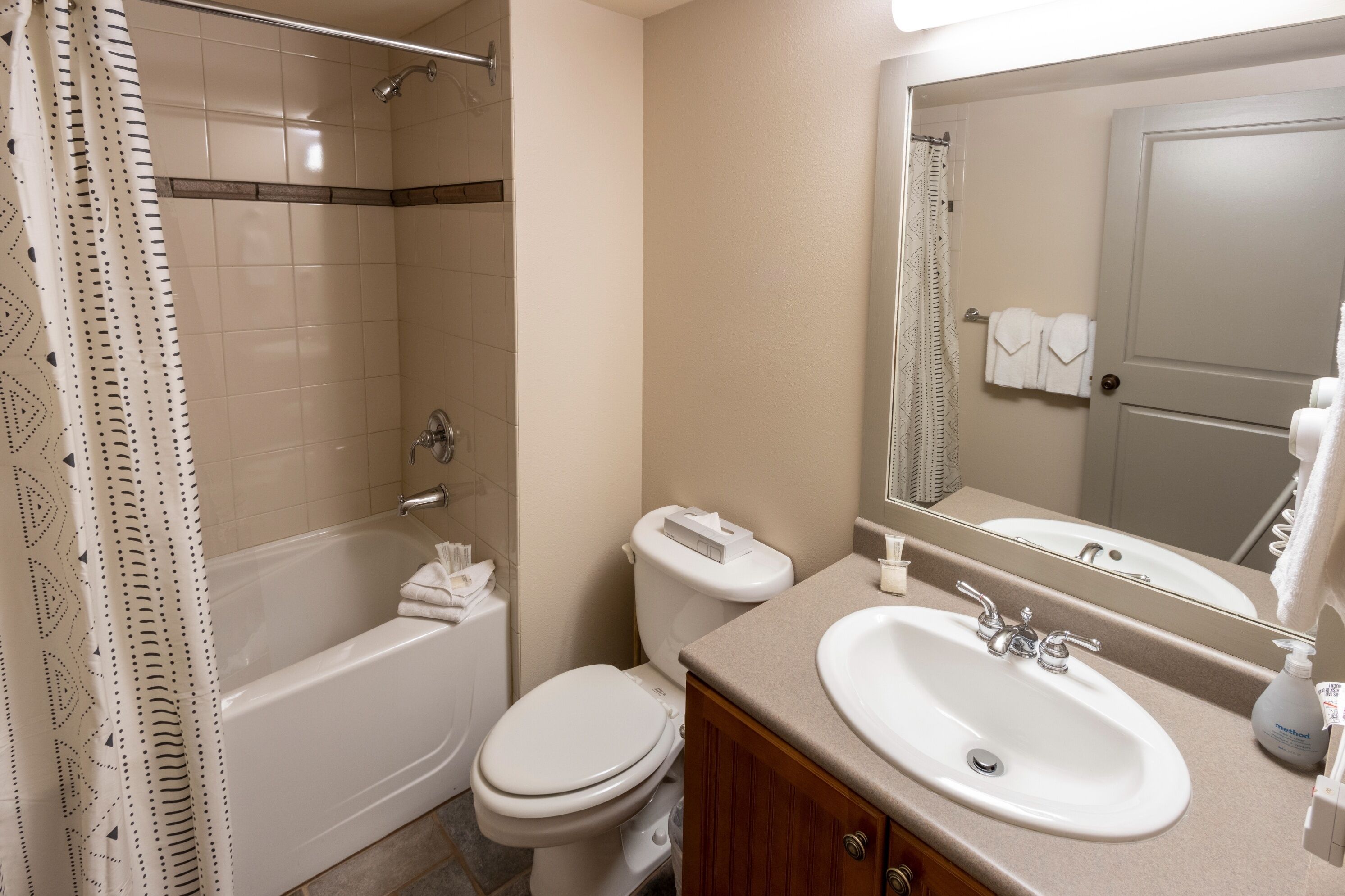 A bathroom with a bathtub, toilet, sink, and a large mirror.