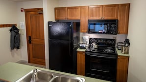 A kitchen with wooden cabinets, a black refrigerator, a microwave, a stove, and a sink. - 2214 - Two Bedroom Standard Eagle Springs East 2 Condo by RedAwning (Solitude)