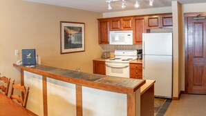 A kitchen with wooden cabinets, a microwave, a stove, and a refrigerator. - 3316 - One Bedroom + Den Standard Powderhorn Lodge 1 Condo by RedAwning (Salt Lake City)