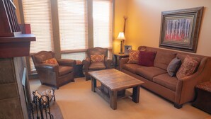 A living room with a brown sofa, two armchairs, a wooden coffee table, and a lamp. - 7401- Three Bedroom + Loft + Den Deluxe Crossings Townhomes 3 Condo by RedAwning (Solitude)