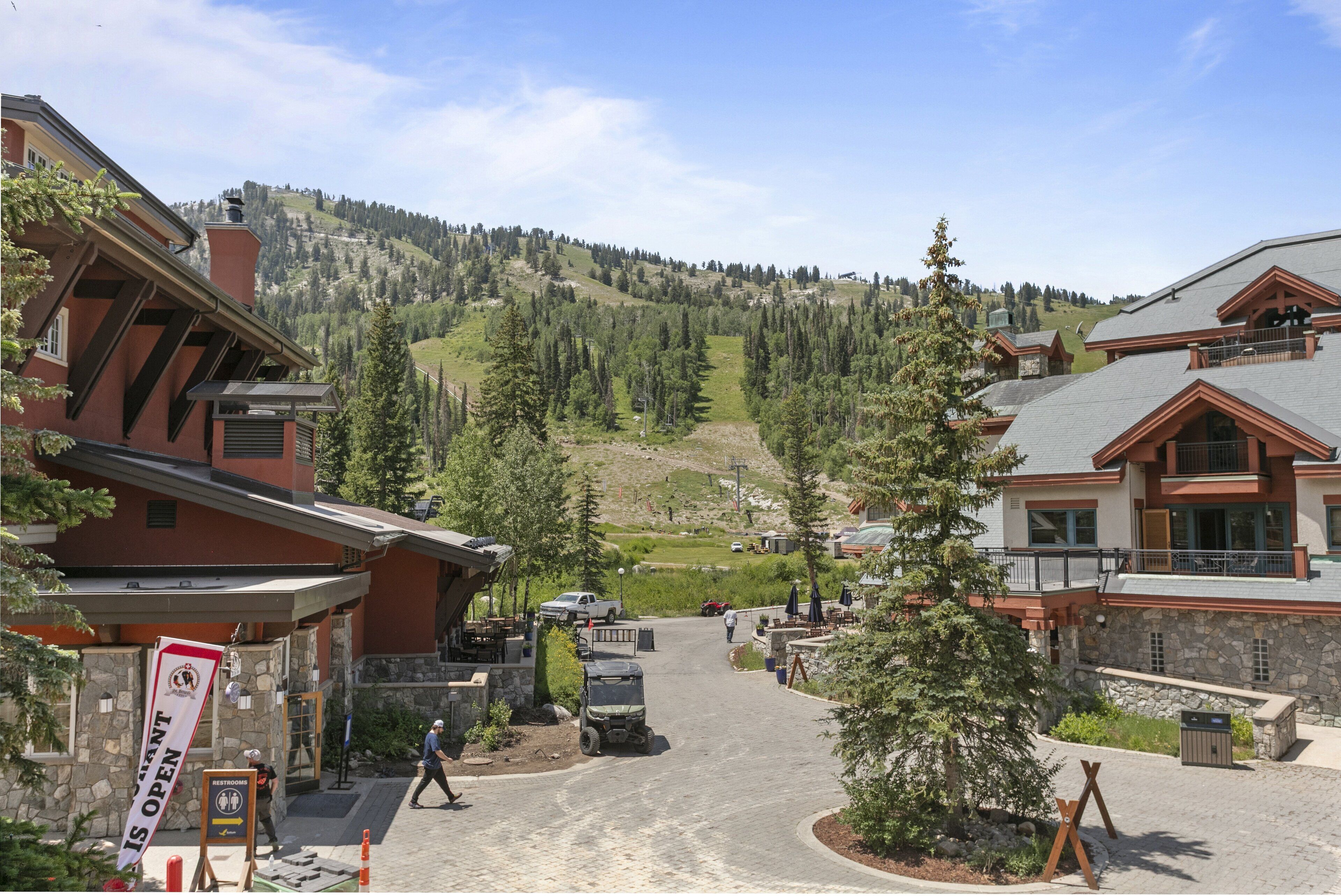 A hotel with a mountain view, a paved driveway, and a sign indicating the restaurant is open.