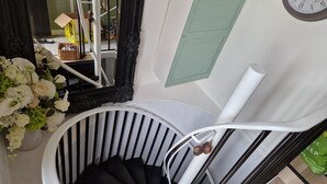A spiral staircase with a black and white railing, a wall-mounted clock, and a mirror with an ornate frame. - Lovely 2-bed Cottage in Coalbrookdale Telford (Telford)
