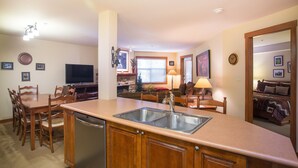 A compact kitchen with a sink, wooden cabinets, and a dining area with chairs and a table. - 3306 - One Bedroom + Den Deluxe Powderhorn Lodge 1 Condo by RedAwning (Salt Lake City)