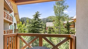 A balcony with a wooden railing and a round table, overlooking a mountainous landscape with trees and buildings. - 3306 - One Bedroom + Den Deluxe Powderhorn Lodge 1 Condo by RedAwning (Salt Lake City)