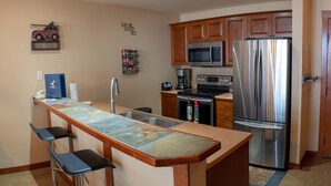 A kitchen with a central island, stainless steel appliances, wooden cabinets, and a microwave. - 3505 - One Bedroom + Den Standard Powderhorn Lodge 1 Condo by RedAwning (Salt Lake City)
