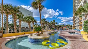 A pool area with multiple water slides, palm trees, and a building in the background.