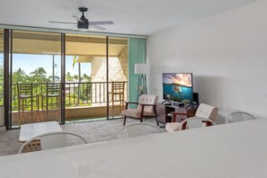 A hotel room with a balcony, a television, and a dining area.