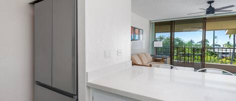 Una cocina moderna con encimera blanca, refrigerador integrado y ventilador de techo.